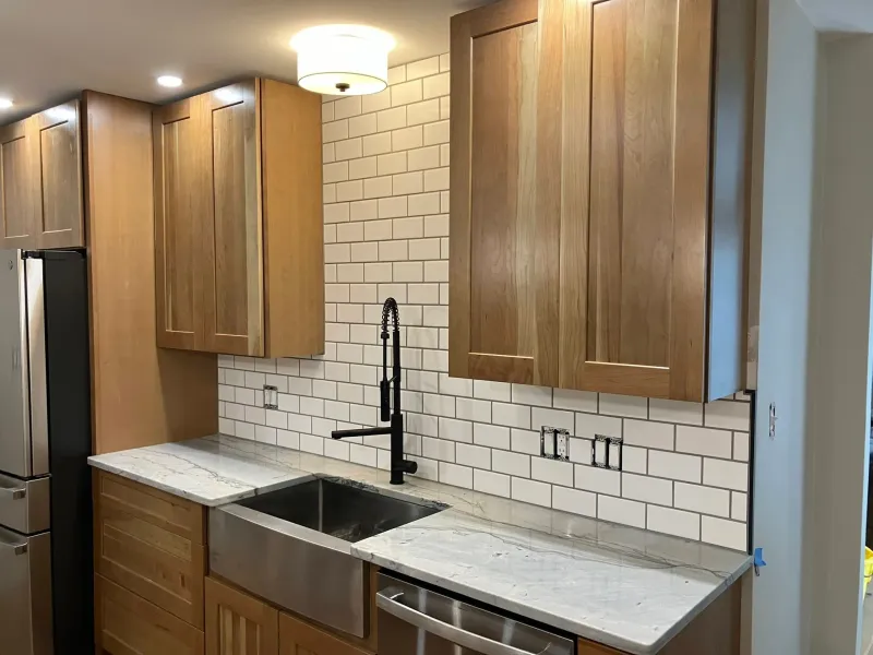 Kitchen sink with wood cabinets and white subway tile